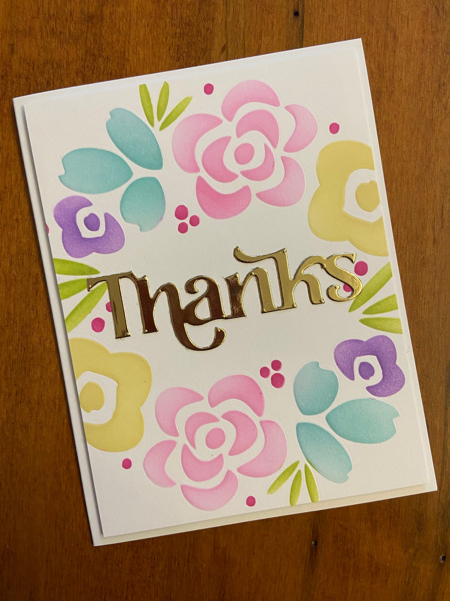 Modern Flowers wreath Thanks handmade card. Ink blended modern flowers in rainbow shades of purple, pink, yellow, green, and turquoise. A thanks die cut sentiment in a metallic gold to finish is placed in the centre of the wreath.