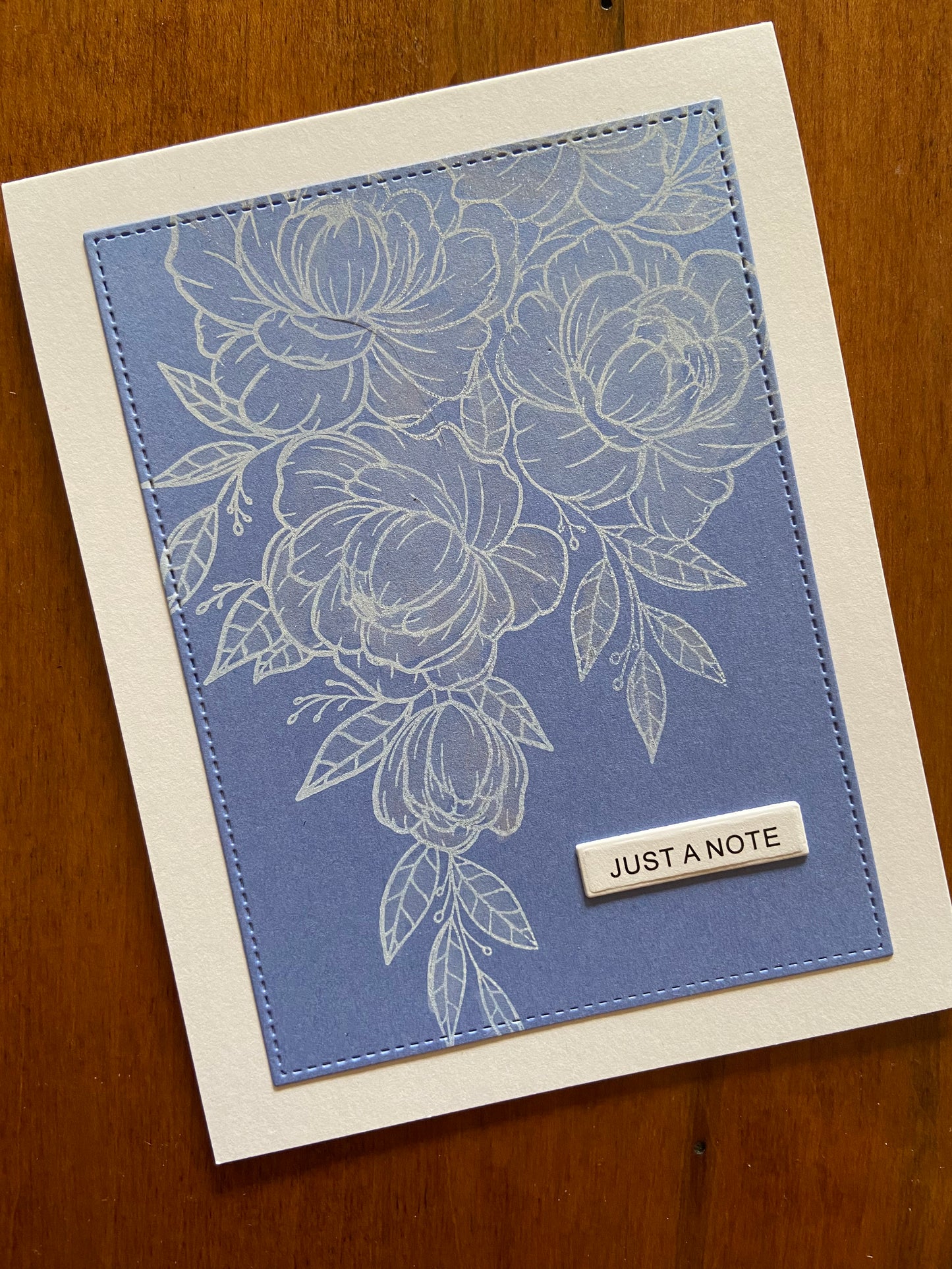 Just a note handmade card. A cornflower blue panel is stamped in white with a large outline spray of flowers and foliage. A little shimmer is applied for some sparkle.