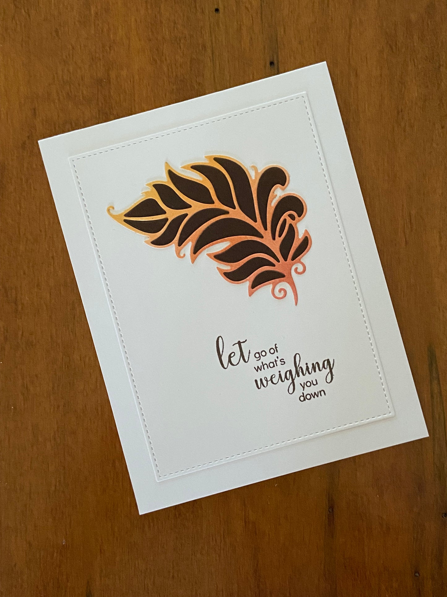 Let go of what’s weighing you down encouragement handmade card. An ink blend of pink, orange, and yellow is die cut in a dainty feather shape and inlaid in chocolate brown.