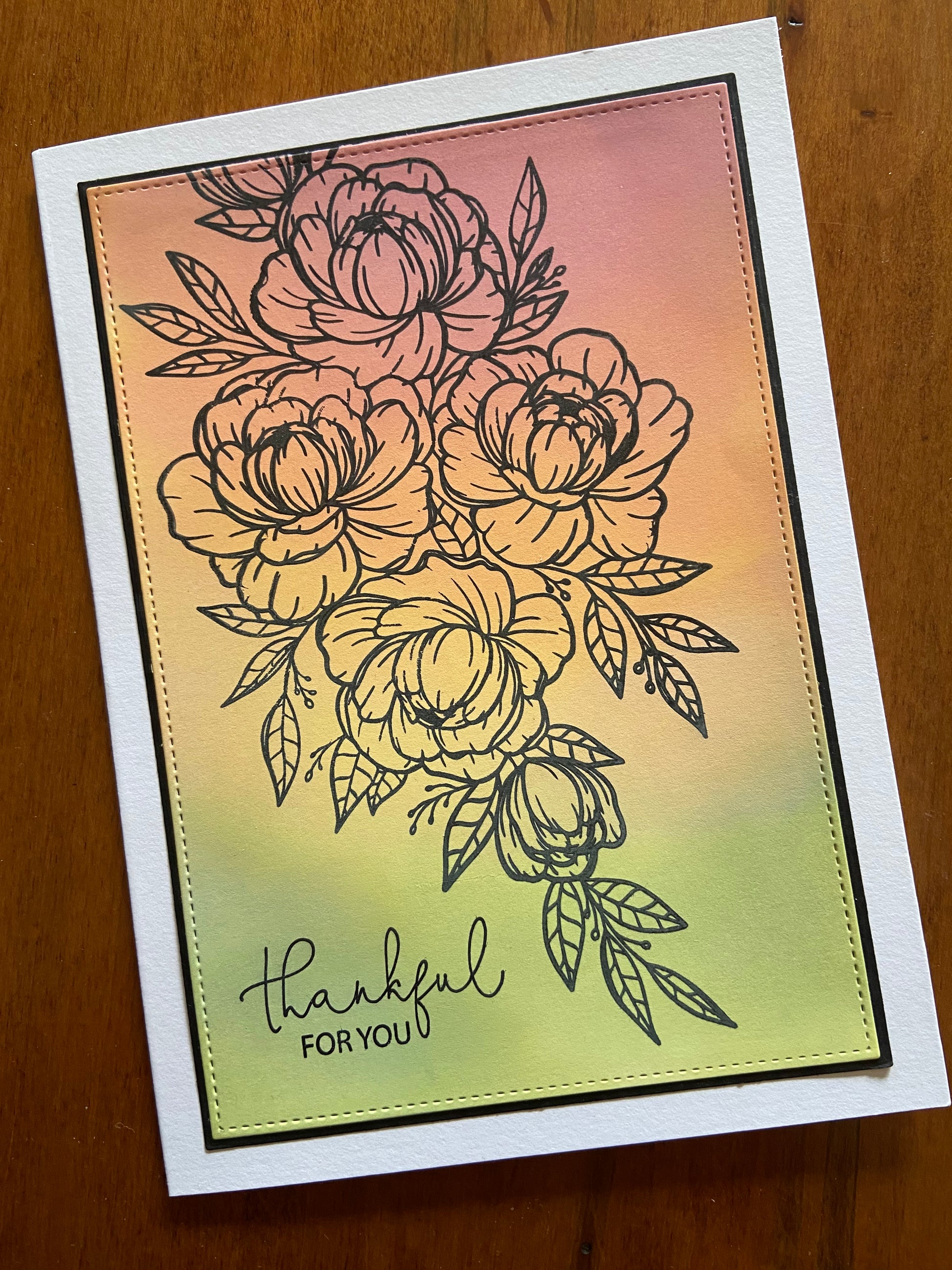 Thankful for you handmade card. A black outline spray of flowers and foliage are stamped across an ink blended background in shades of green, yellow and pink.