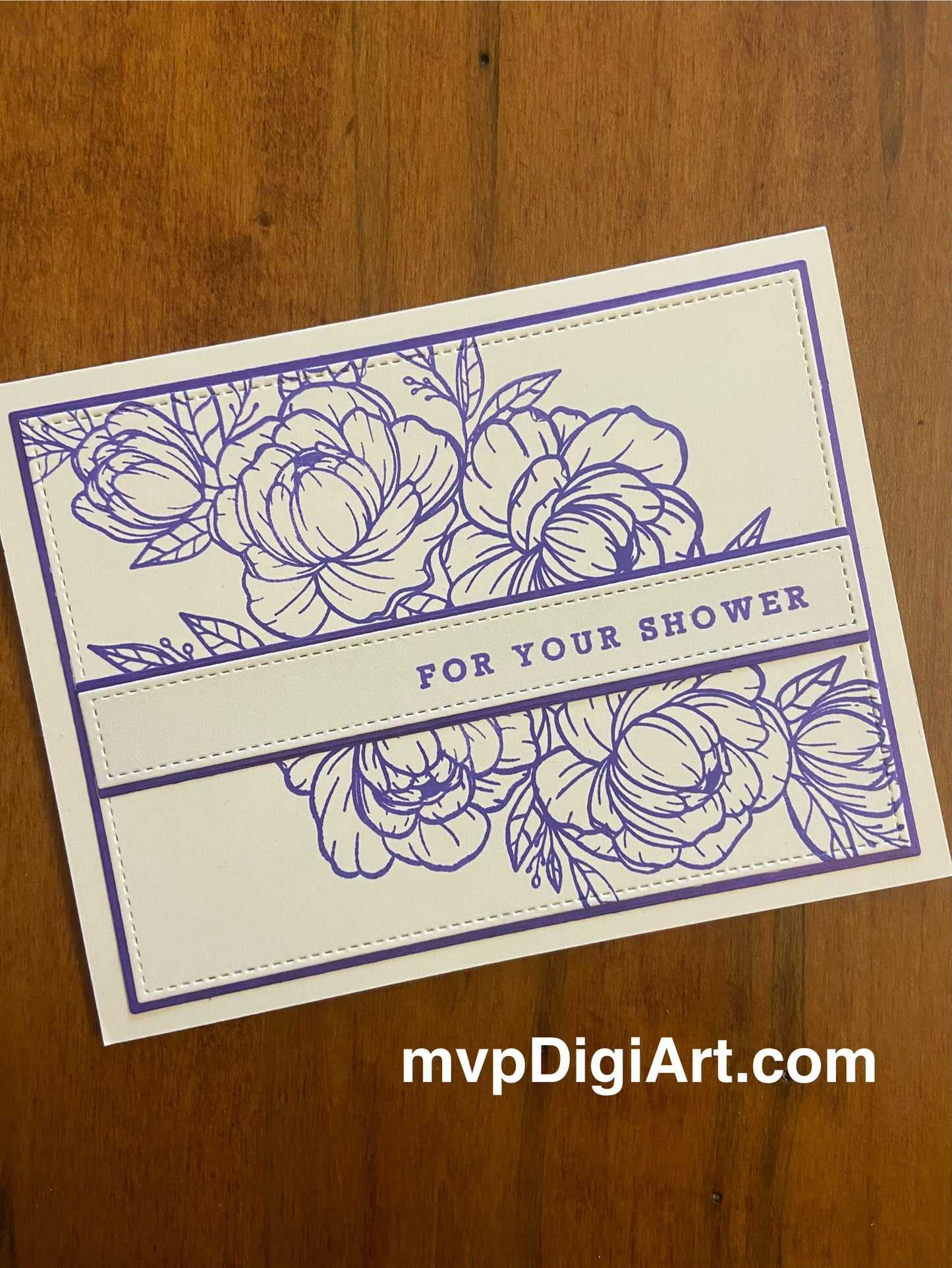 An ivory and purple wedding shower card featuring a stamped purple outline of flowers and greenery. A sentiment strip that reads "for your shower" stretches across the design. The main panel and sentiment strip are matted in purple.