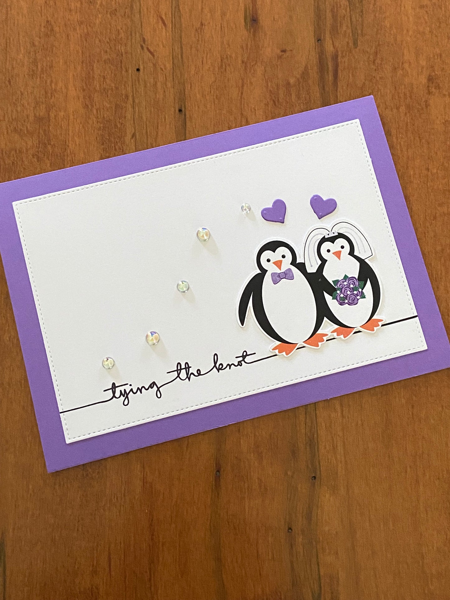 Tying the Knot Wedding Card purple and white Handmade card; penguin bride & groom with purple hearts above them. Some sparkle is introduced using some shiny pearls across the front