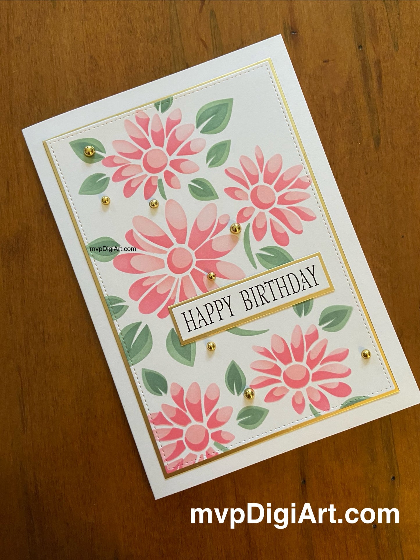 Handmade card with pink ink blended daisies and green leaves; matted in gold. A simple happy birthday sentiment is printed in black and also matted in gold. Gold tone pearls add sparkle and dimension.
