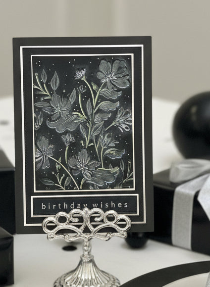 Black and silver vloral card with 'birthday wishes' text on a decorative stand.