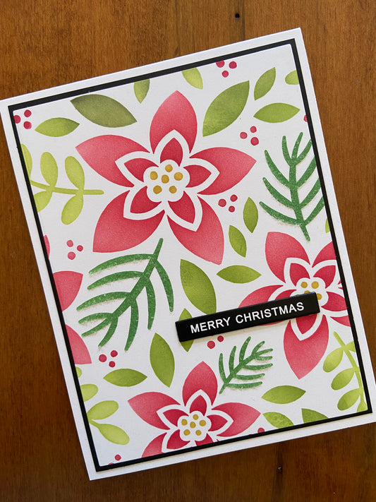 Handmade Christmas card with contemporary red poinsettia flower and greenery on white background with gold 'Merry Christmas' text