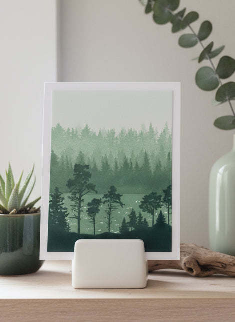 All occasion card with forest and lake scene displayed on a decorative stand with natural elements and greenery