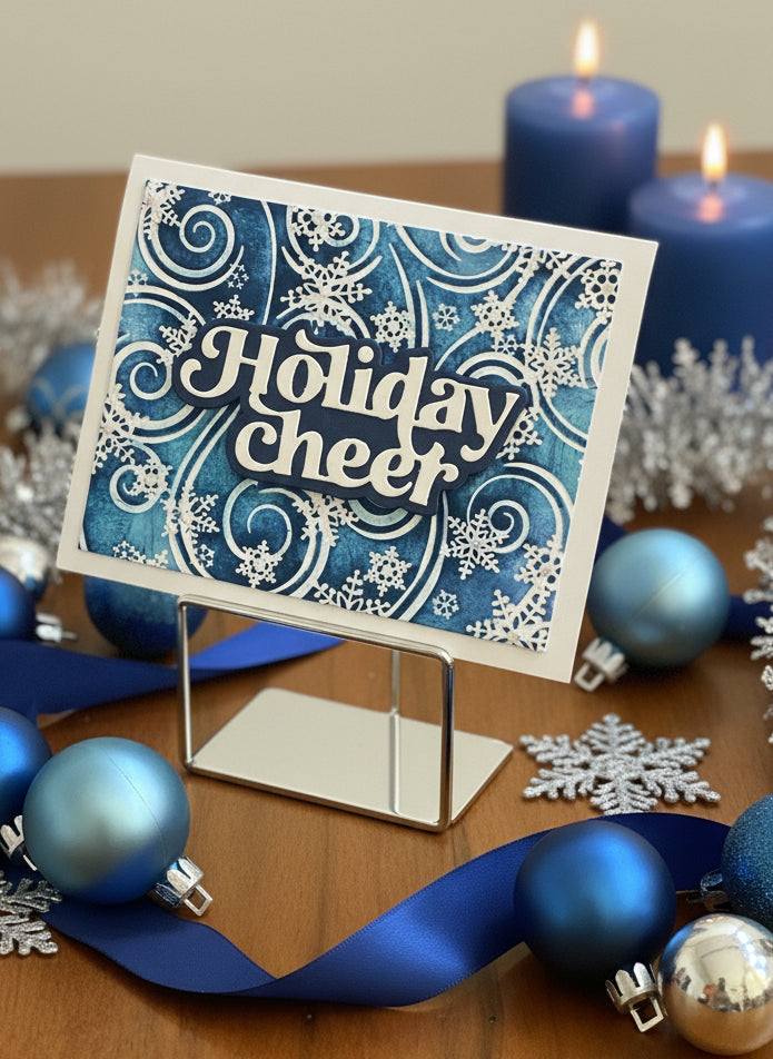 Christmas card with blue and white snowflakes and Holiday Cheer sentiment displayed with festive holiday decorations