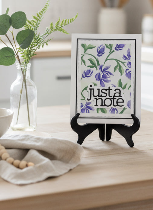 Greeting card with purple flowers and 'just a note' text on a decorated table