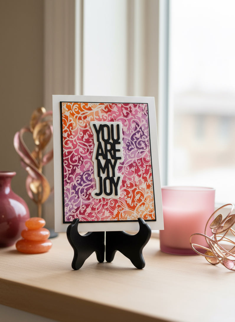 Handmade greeting card with 'You Are My Joy' text on colourful funky patterned background displayed on a decorated shelf