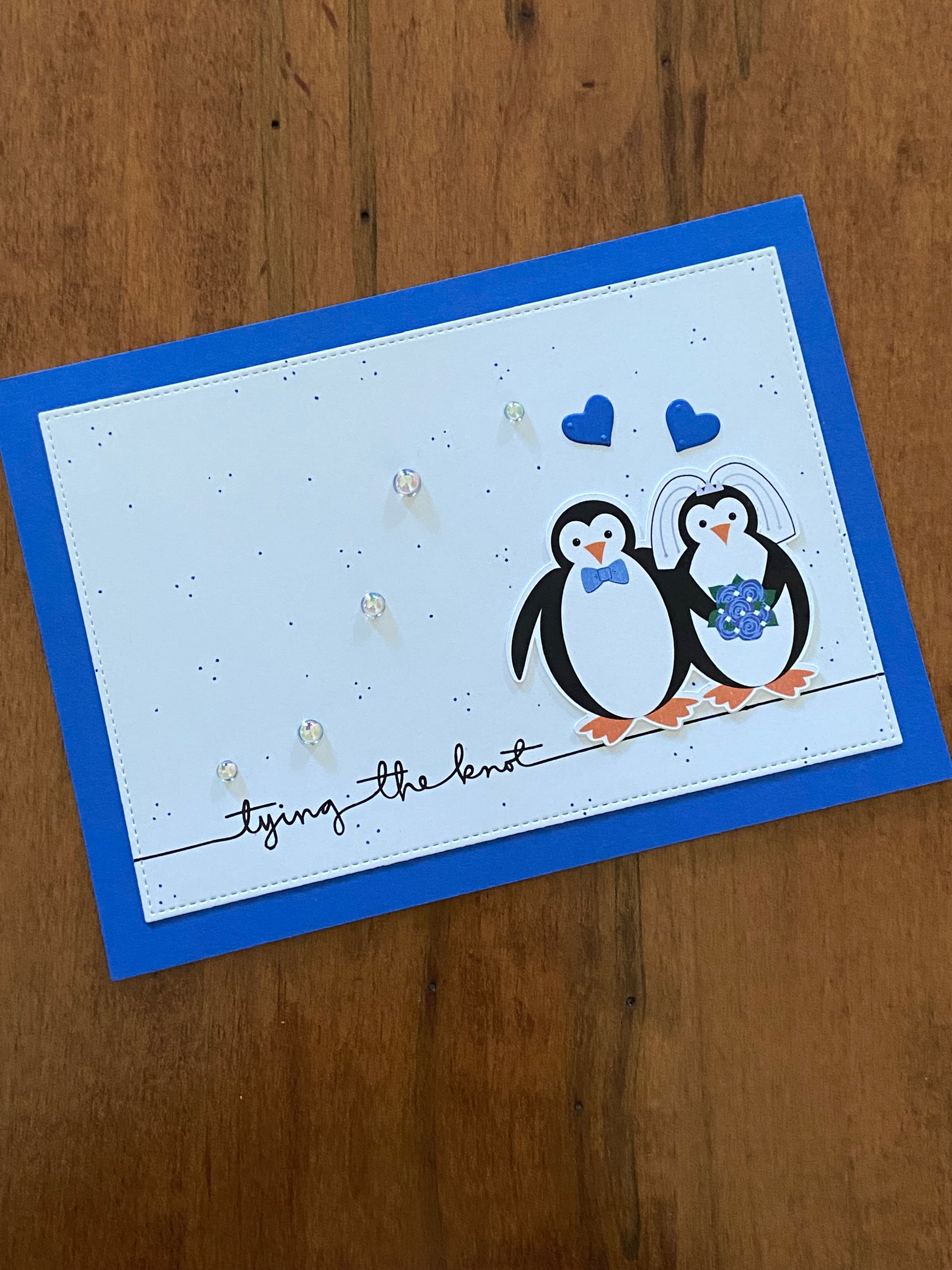 Tying the Knot Wedding Card blue and white Handmade card; penguin bride & groom with blue hearts above them. The white background has tiny blue dots throughout. A little sparkle from some shiny pearls.