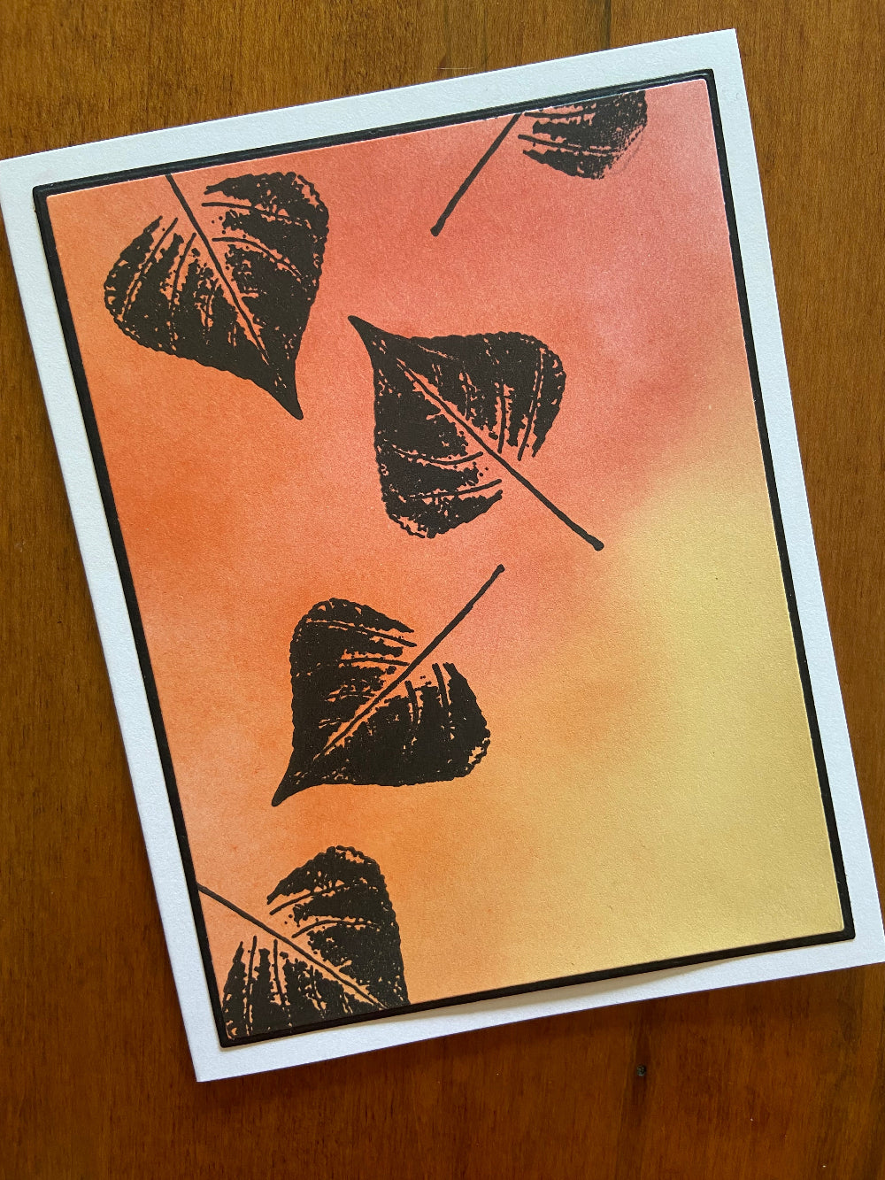 Autumnal oranges, yellows, and reds are ink blended together. 4 Black silhouette leaves are stamped here and there. 