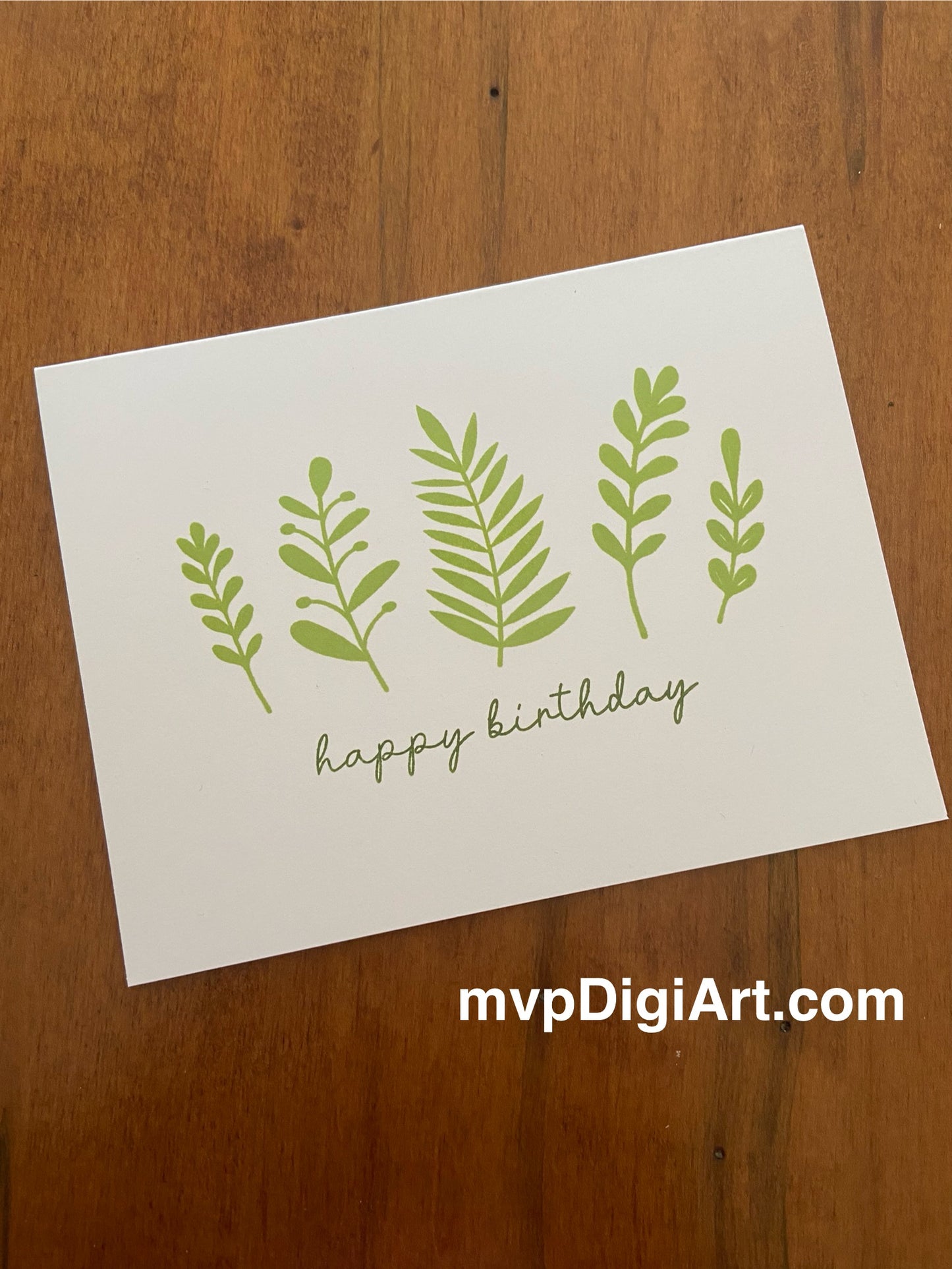 Happy birthday card with hand-stamped green botanical design and cursive sentiment.
