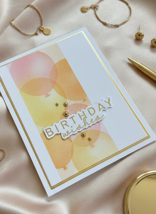 Birthday card with balloons and 'Happy Birthday' text on a satin surface with jewelry.