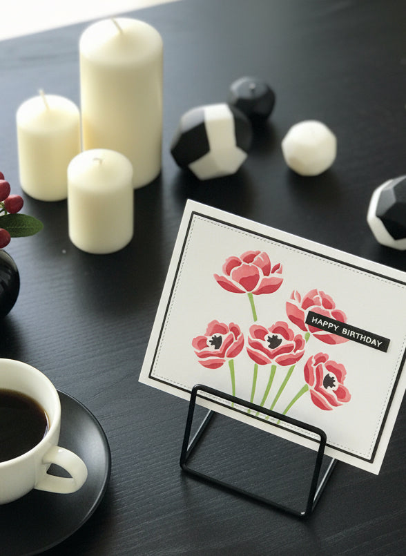Handmade birthday card with red poppies on white background displayed on coffee table