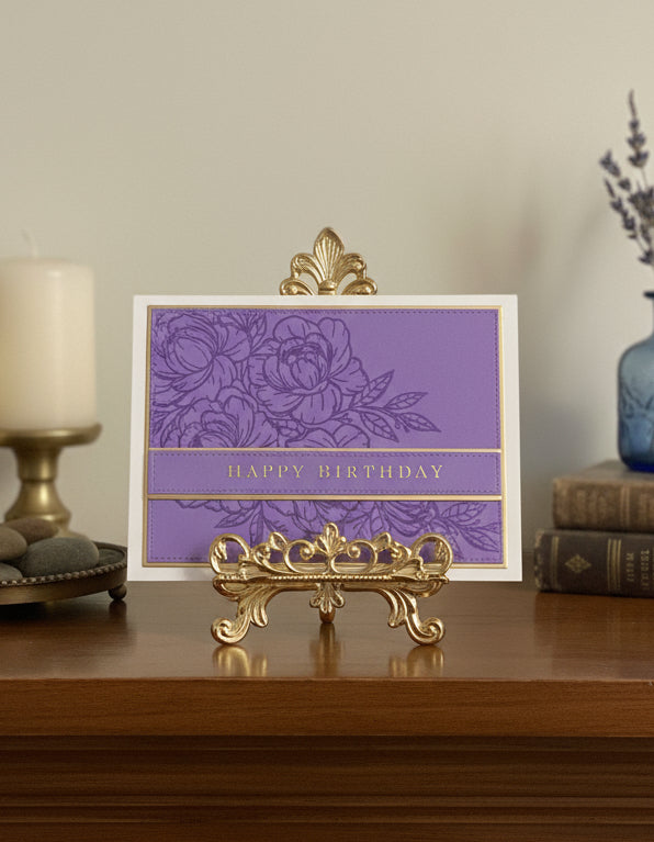 Purple birthday card with gold floral design on a decorative stand