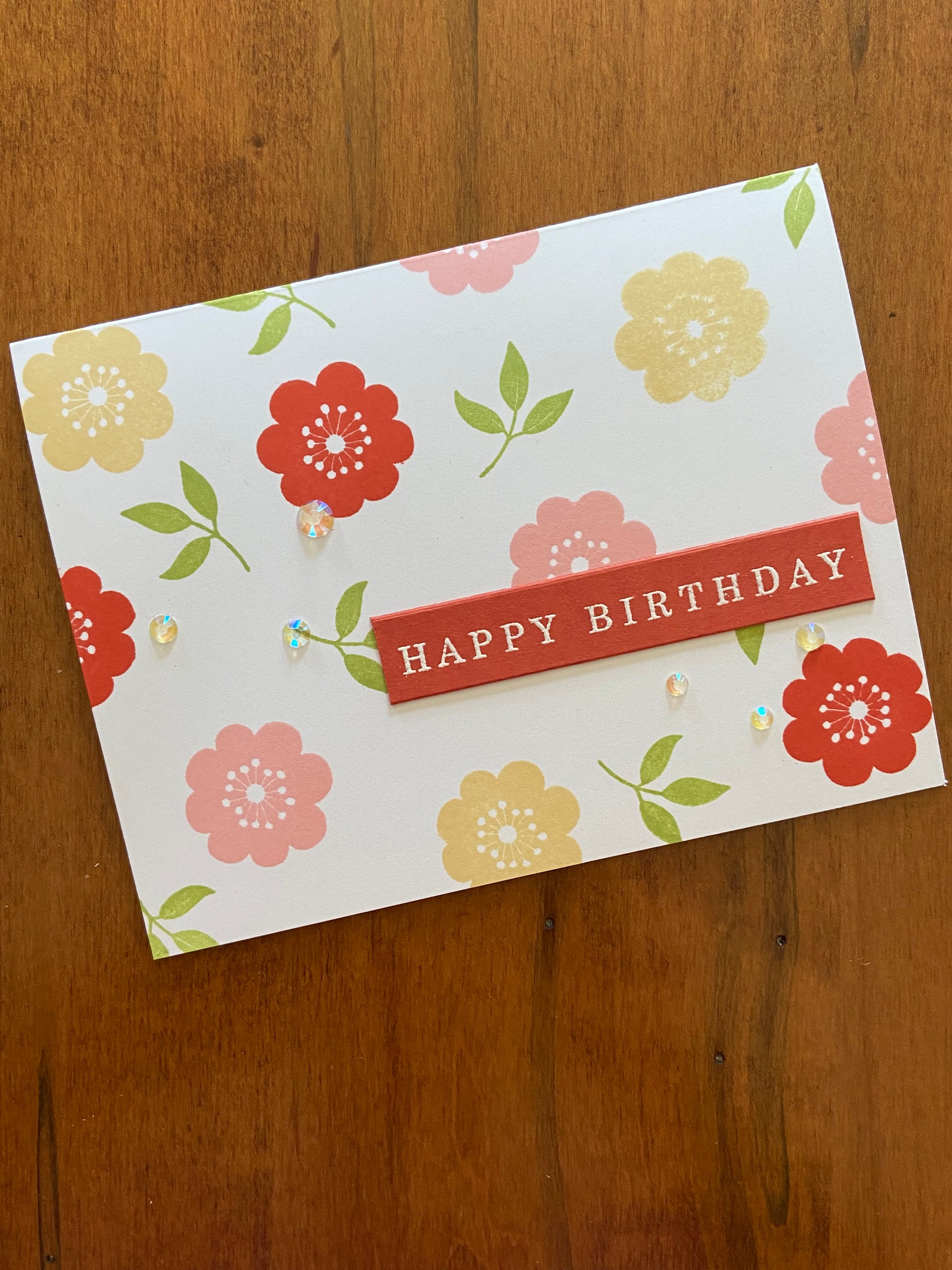 Handmade birthday card with yellow, pink and mahogany floral stamps, greenery and crystal gems