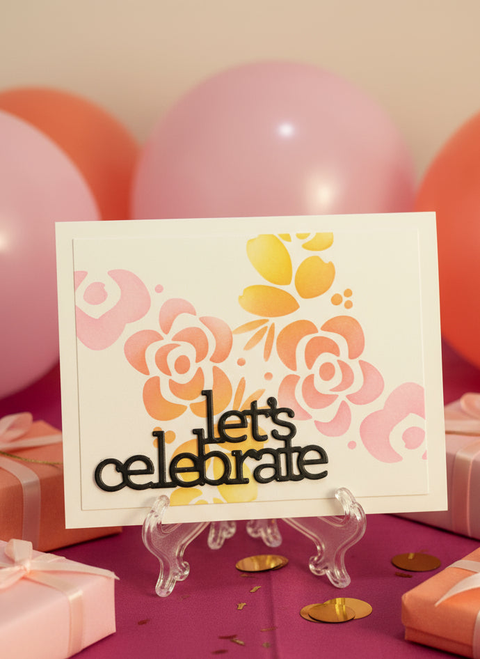 Card with floral design and 'let's celebrate' text in front of balloons and gifts.