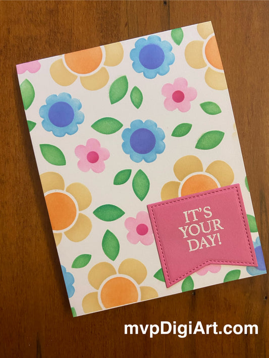 A handmade greeting card with a floral pattern and a pink flag that reads 'IT'S YOUR DAY'.