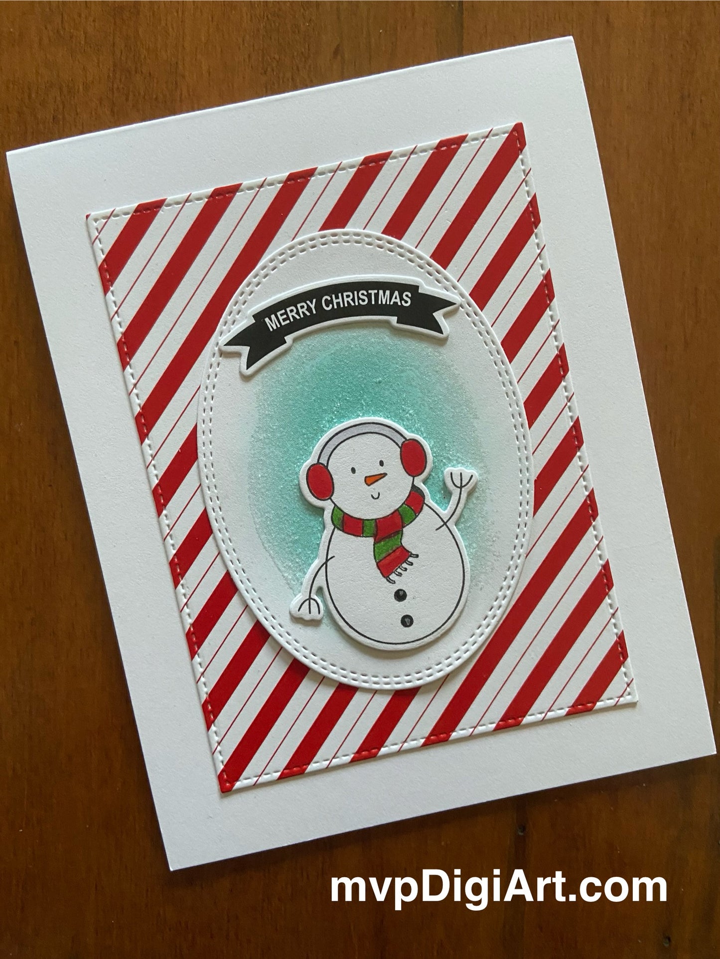 Handmade Christmas card with cute snowman character on candy cane striped background and Merry Christmas banner