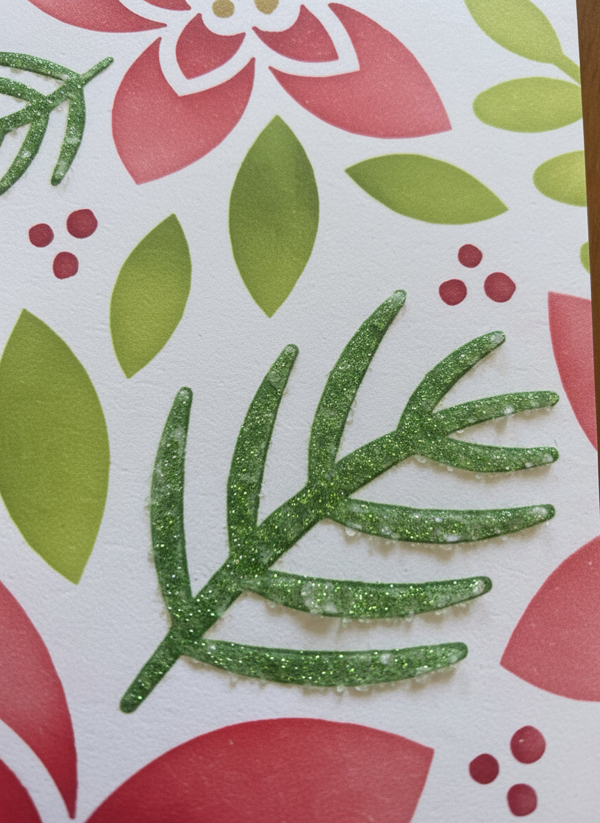 Close-up detail of Christmas card showing modern poinsettia design with red and green flowers and leaves