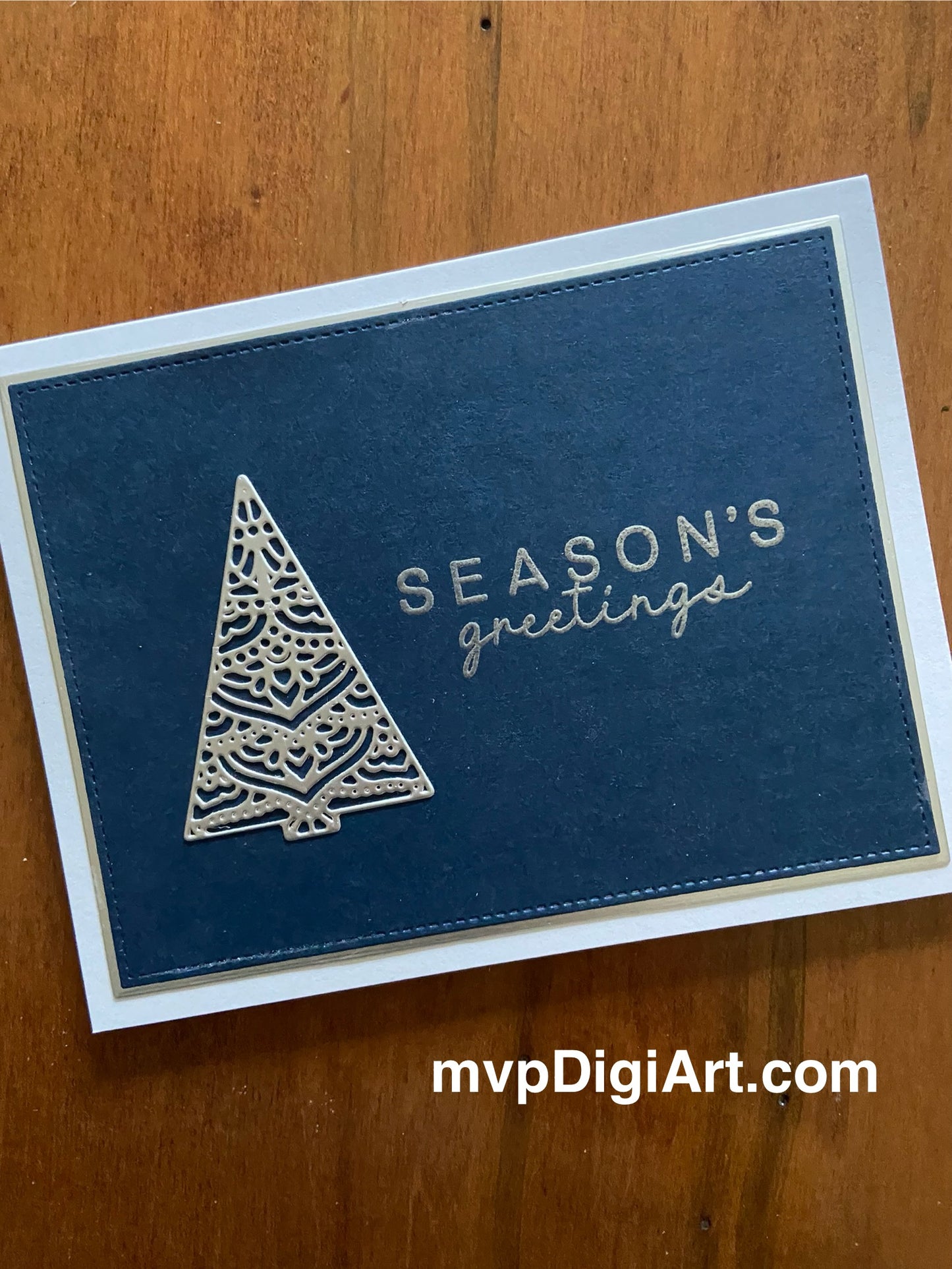 Handmade Christmas card with ornate silver filigree tree on navy blue background with stitched border and heat-embossed Season's Greetings sentiment