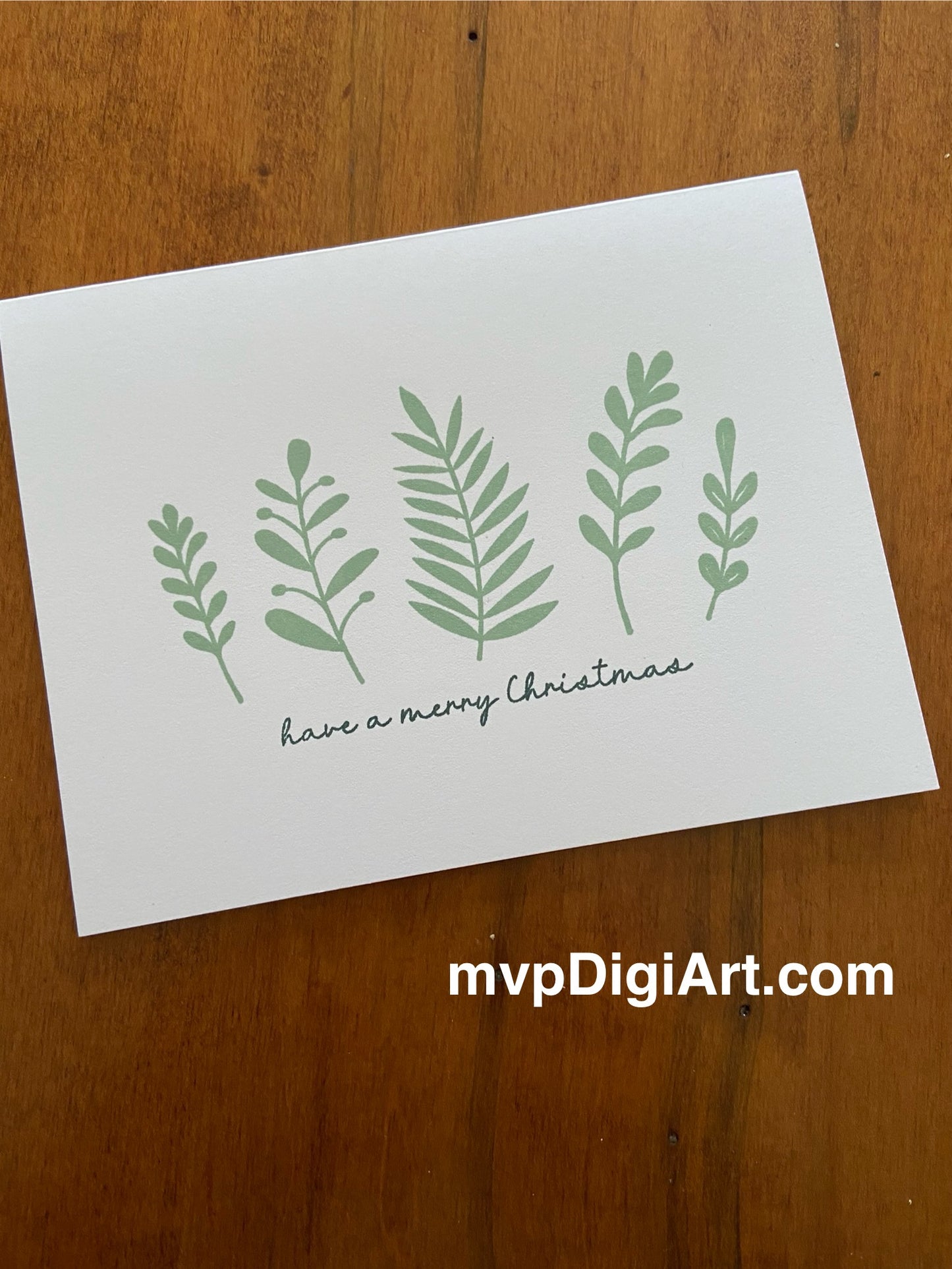 Handmade Christmas card with mixed botanical foliage in spruce green tones and 'Merry Christmas' sentiment on white background