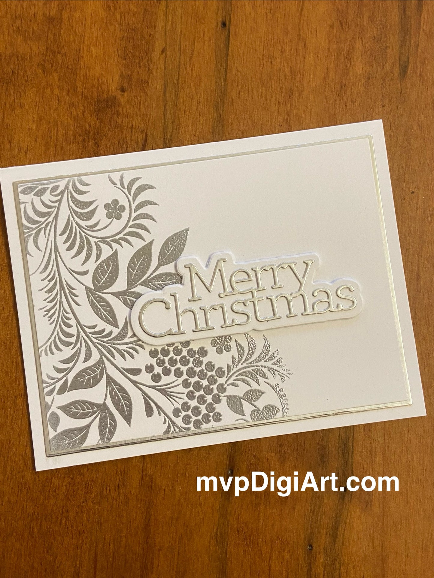 Handmade Christmas card with metallic embossed botanical foliage in silver and white with 'Merry Christmas' sentiment