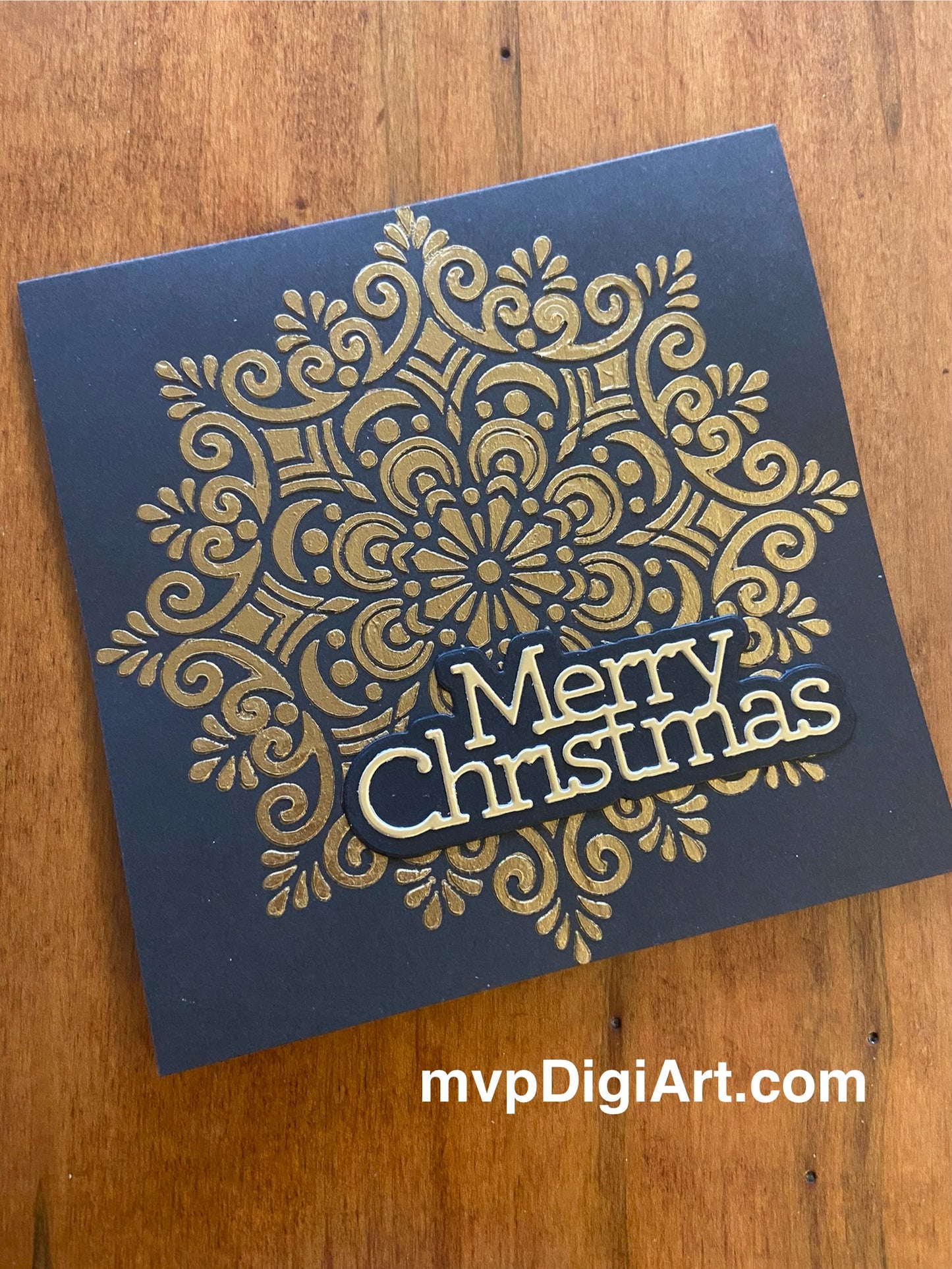 A handmade square Christmas card with a large gold snowflake design on a black background with 'Merry Christmas' text
