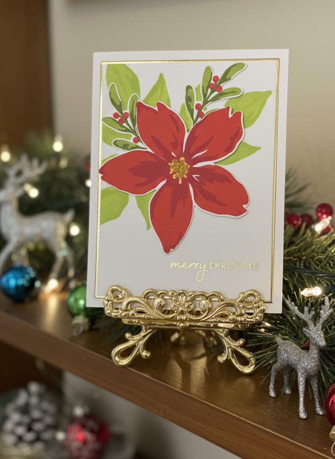 Christmas card with poinsettia design on a decorative stand, surrounded by festive decorations.