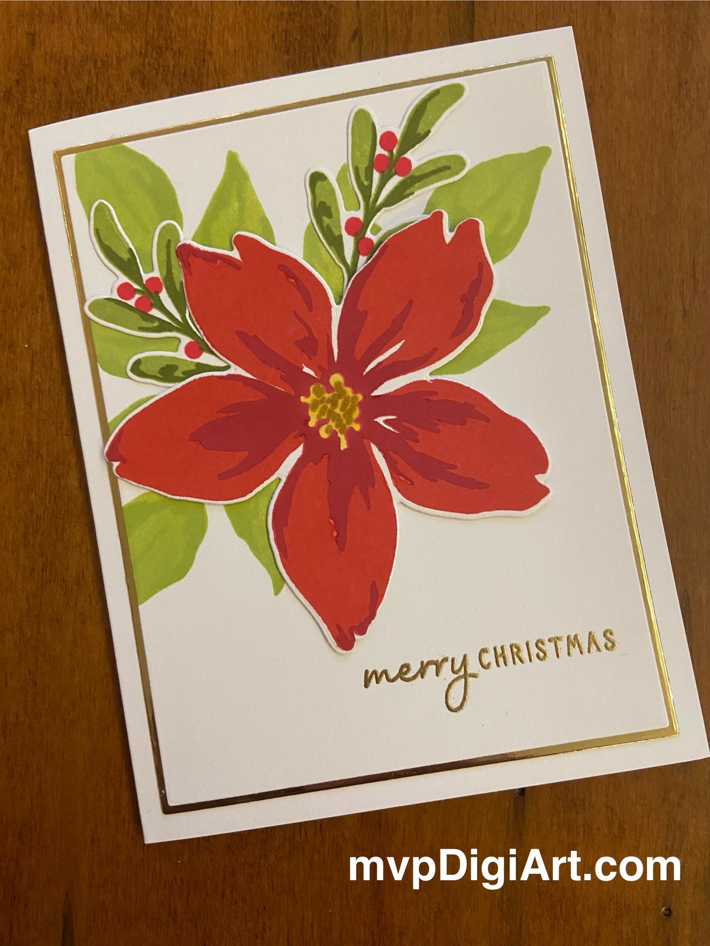 A handmade Christmas card with a gold matted panel featuring a red poinsettia bloom and greenery, along with the text 'Merry Christmas' on the front.