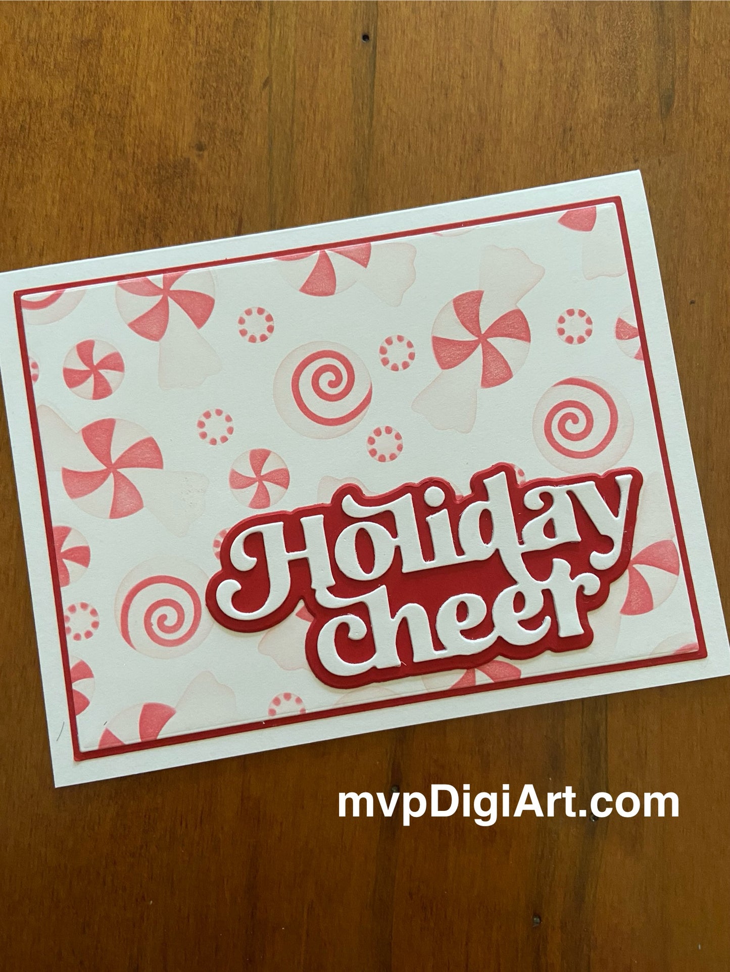 A Christmas card with a peppermint candy background and the text 'Holiday Cheer' on a red shadowed background. The card also features a die cut sentiment and some decorative elements.