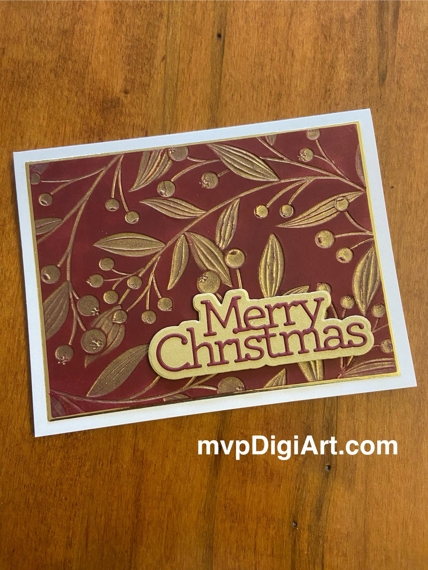 A handmade Christmas card with a red panel featuring gold twining berries and leaves, and the text 'Merry Christmas' die-cut in red cardstock on gold