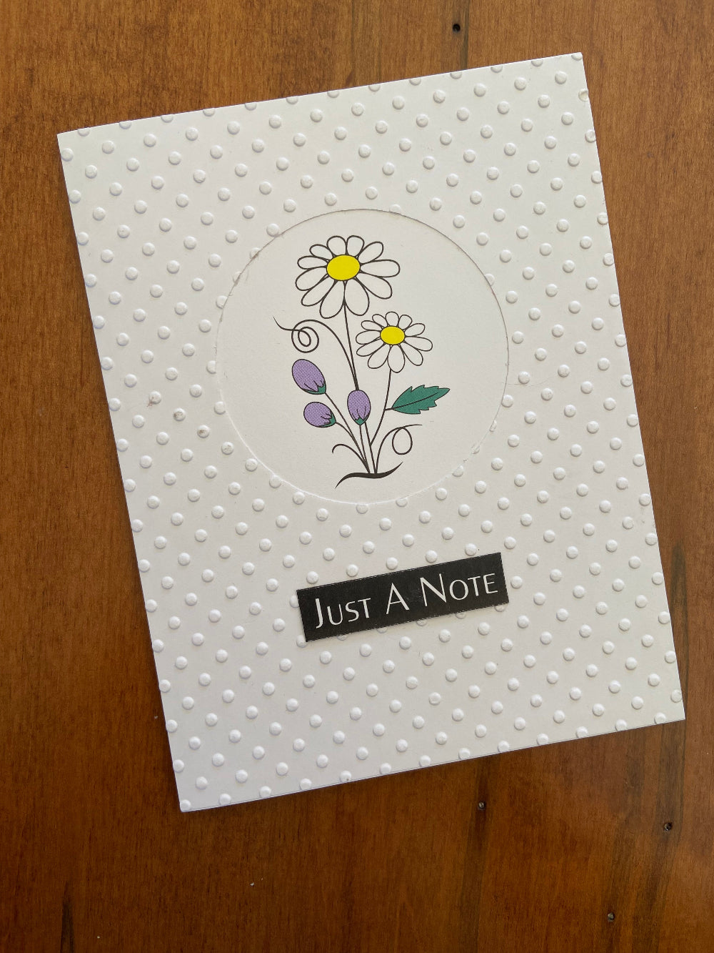 Just a note floral handmade card. The panel is in Swiss dot embossed pattern with a circular window revealing sweet daisies and bluebell flowers. 