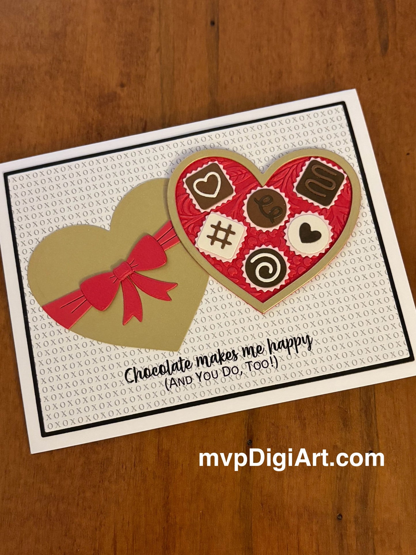 Card with heart-shaped chocolate box with lid and candy design on a soft grey XOXO backgound and text 'Chocolate makes me happy and so do you'