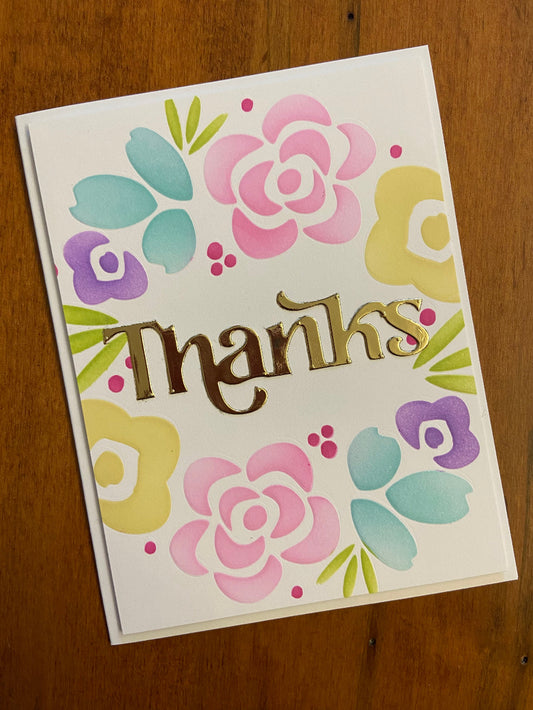 Modern Flowers wreath Thanks  handmade card. Ink blended modern flowers in rainbow shades of purple, pink, yellow, green, and turquoise. A thanks die cut sentiment in a metallic gold to finish is placed in the centre of the wreath. 