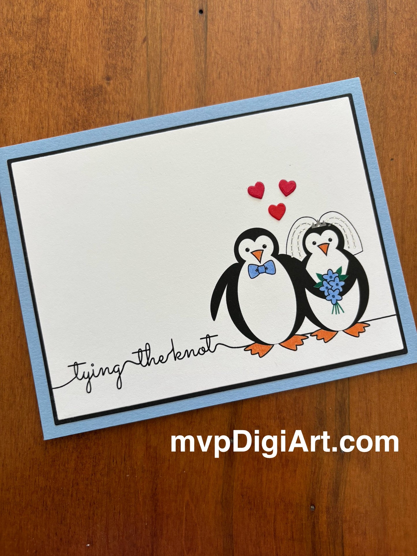 Card with penguins couple with red hearts, original artwork, and text 'tying the knot' on a light blue note card