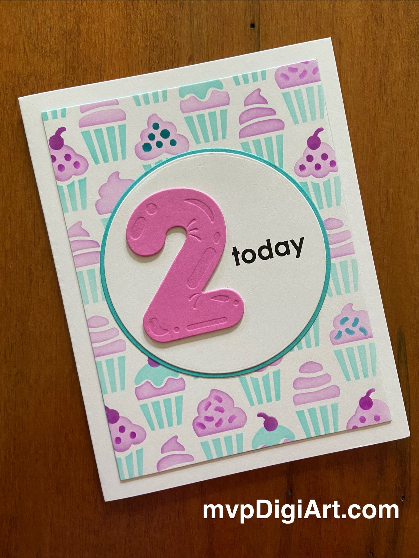 A handmade birthday card with a cupcake pattern, featuring a pink die cut number '2' and the phrase 'today' on a turquoise background, adhered to a white notecard.
