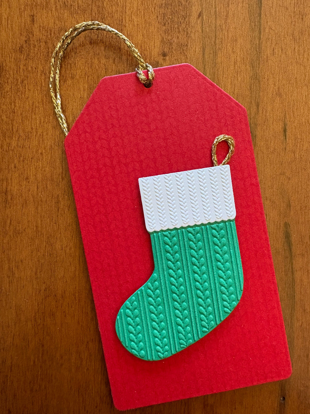 Red gift card holder tag with a green and white textured stocking and a gold string