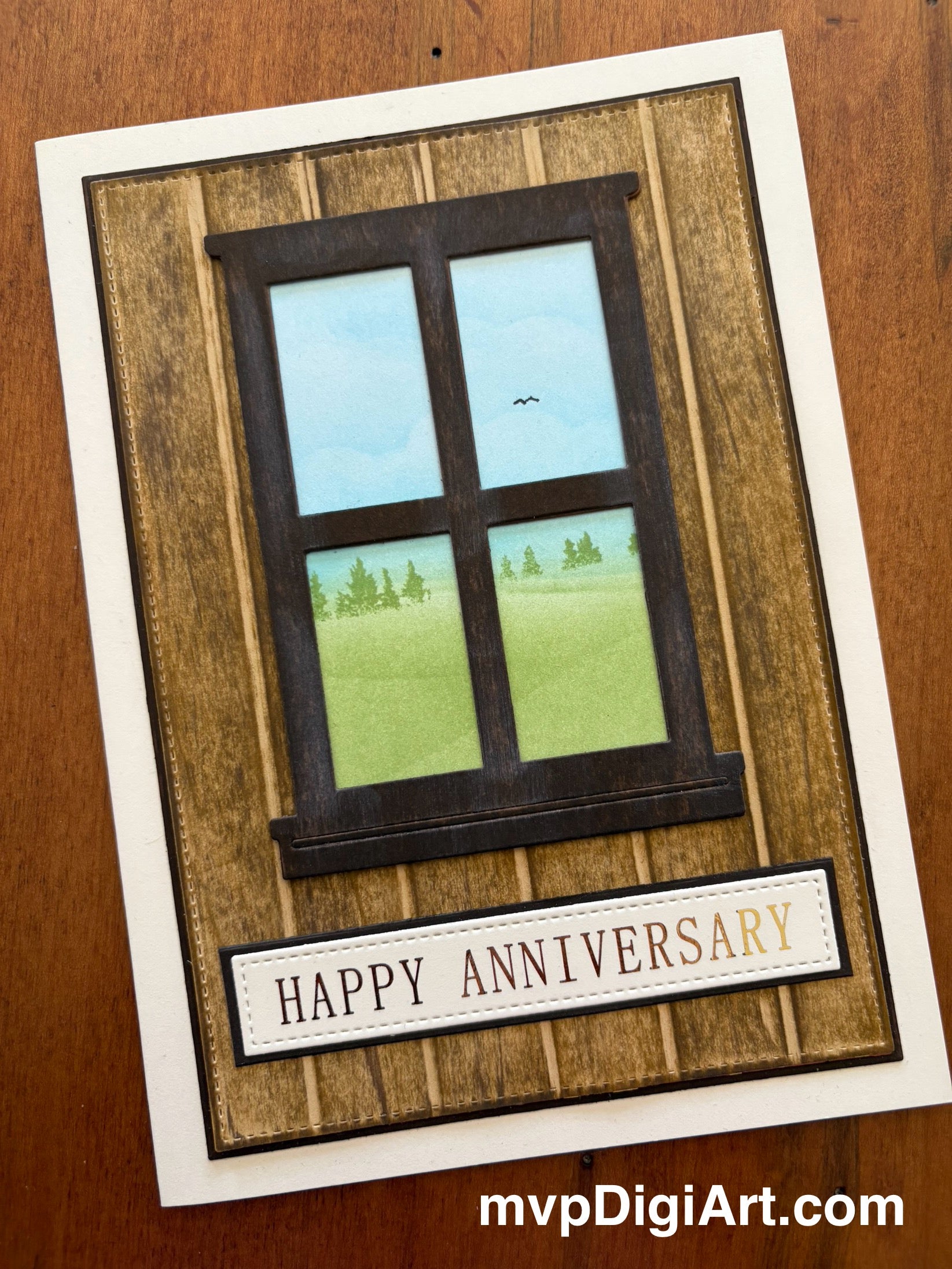 Handmade anniversary card with woodgrain frame and window to nature scene, text below ‘happy ‘anniversary’ in gold