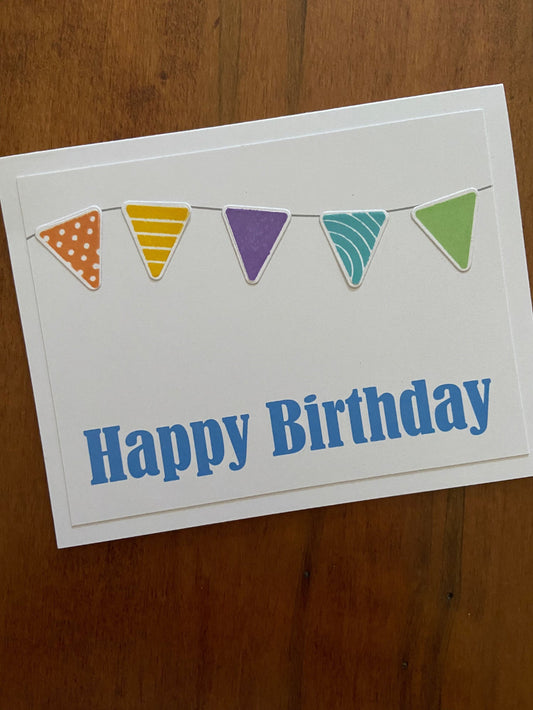 Birthday card with colourful triangle flags and blue 'Happy Birthday' text on a white notecard
