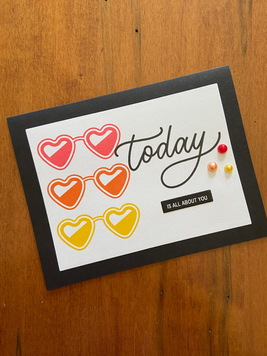 Today is all about you birthday/celebration card; three heart shaped sunglasses in yellow, orange and red stamped on the front of a white panel adhered to a black note card. Three coordinating red,yellow and orange pearls are added to add dimension and a little glitz.