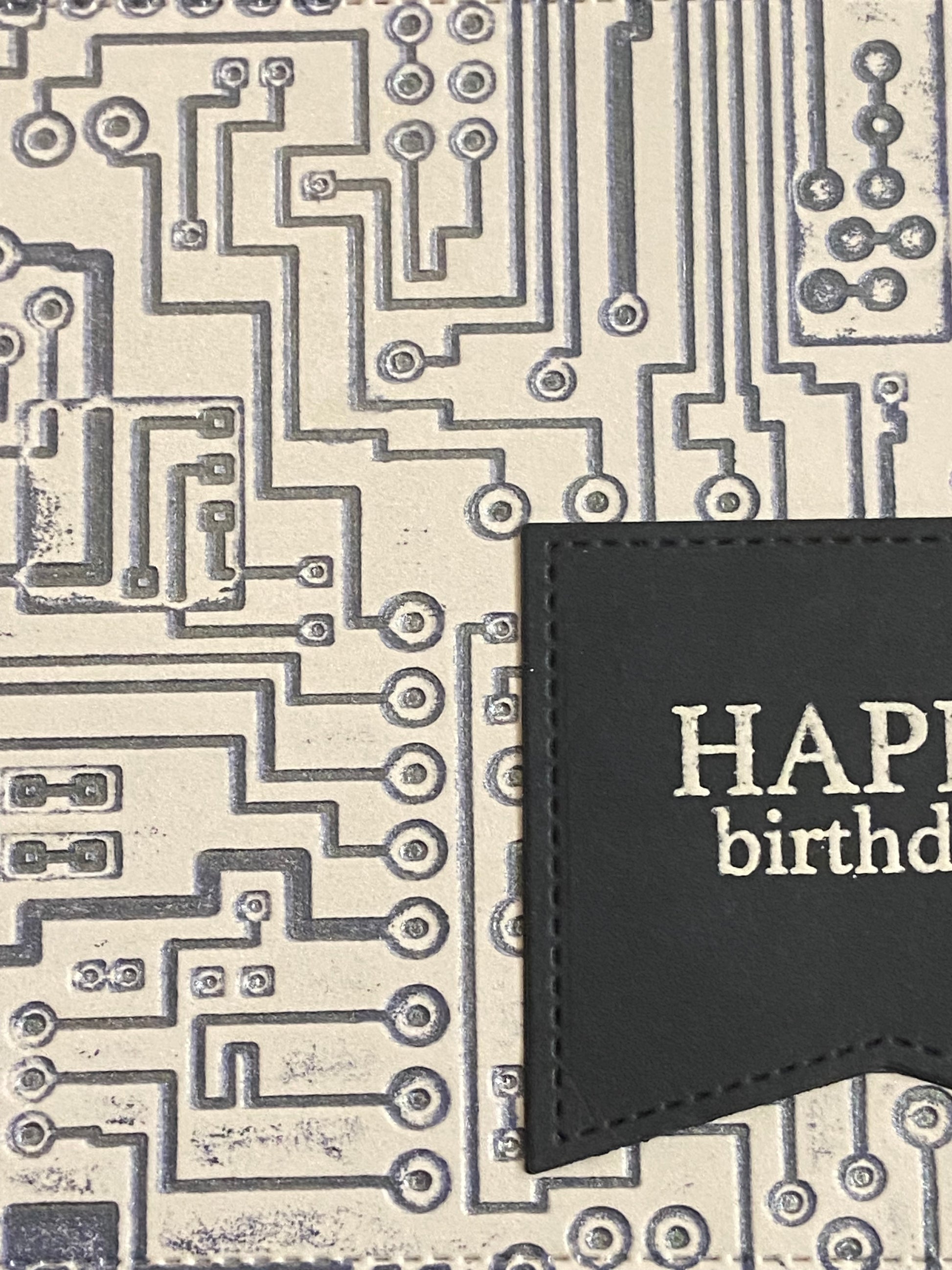 Close-up detail of handmade birthday card showing dark blue circuit board pattern and die-cut sentiment flag with white text