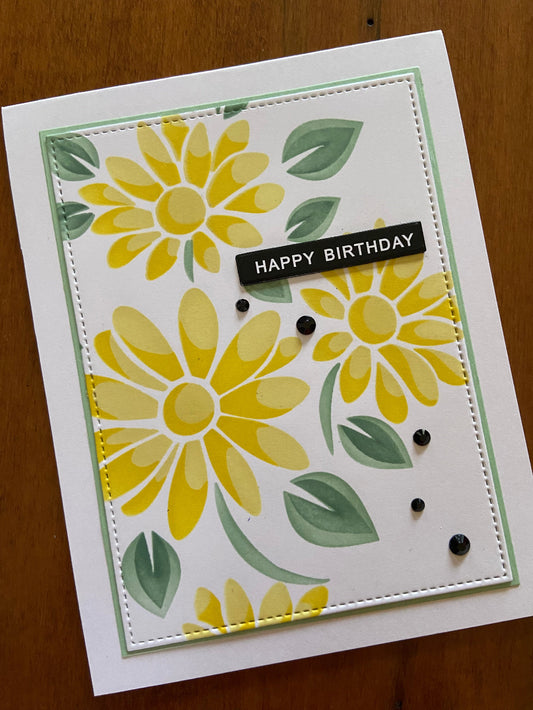 Handmade yellow daisy birthday card with hand-stencilled floral design, green matted panel, black crystals, and happy birthday sentiment on white background