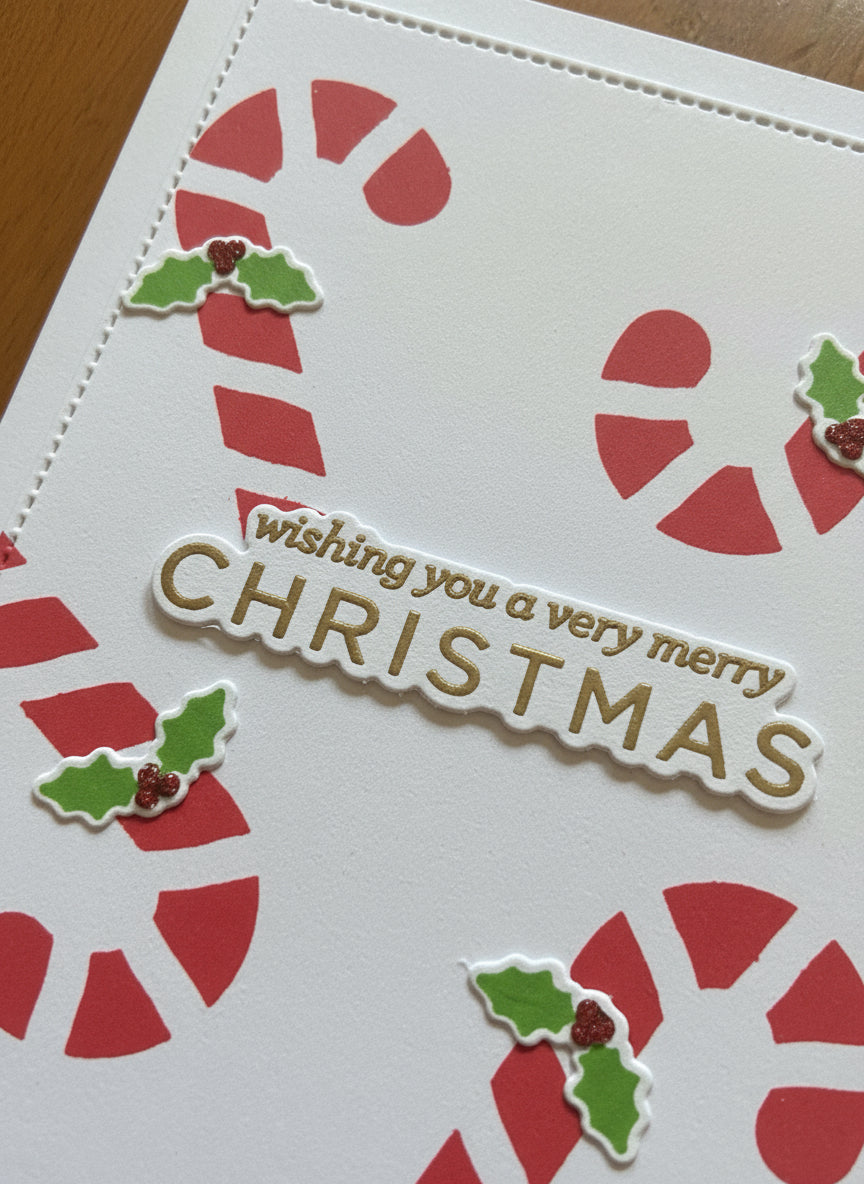 Close-up detail of Christmas card showing candy canes and holly decorations with gold heat embossed sentiment
