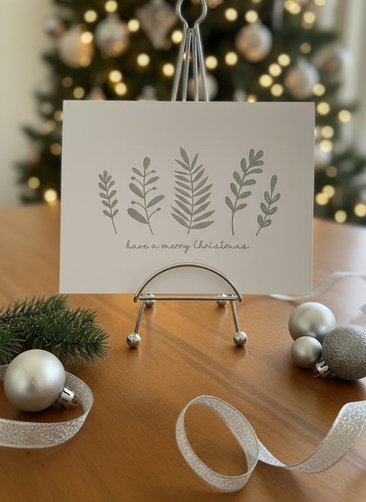 Christmas card with silver botanical foliage displayed with simple holiday decorations