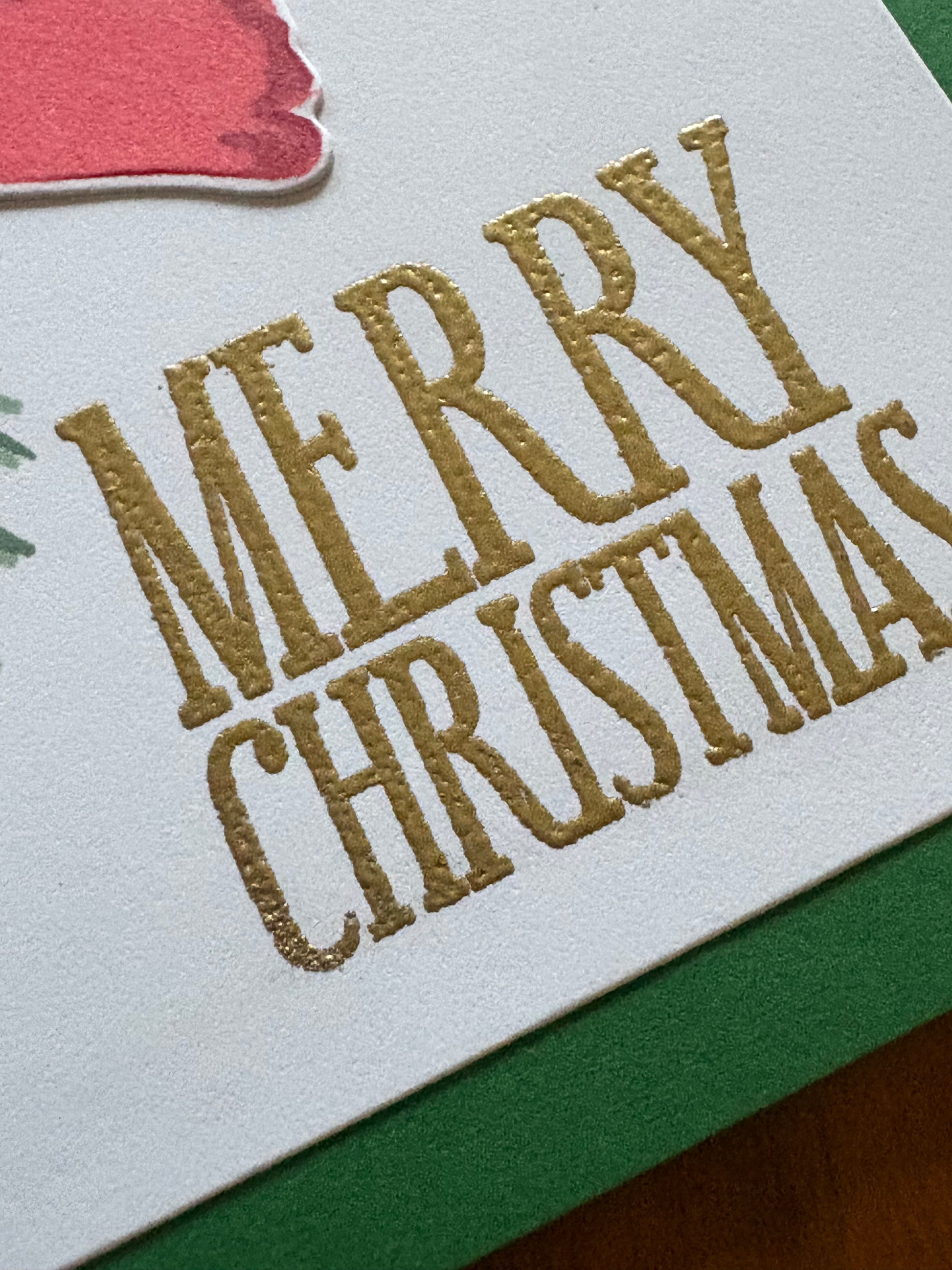 Christmas card with poinsettia and pine spruce design displayed with festive holiday decorations