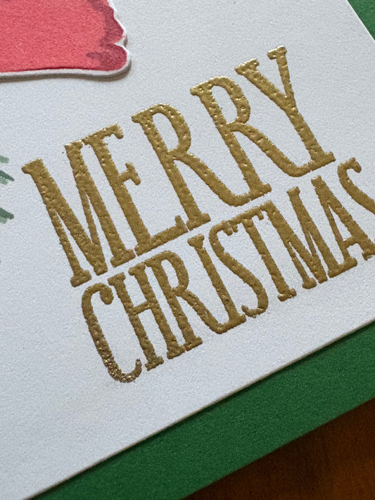 Christmas card with poinsettia and pine spruce design displayed with festive holiday decorations