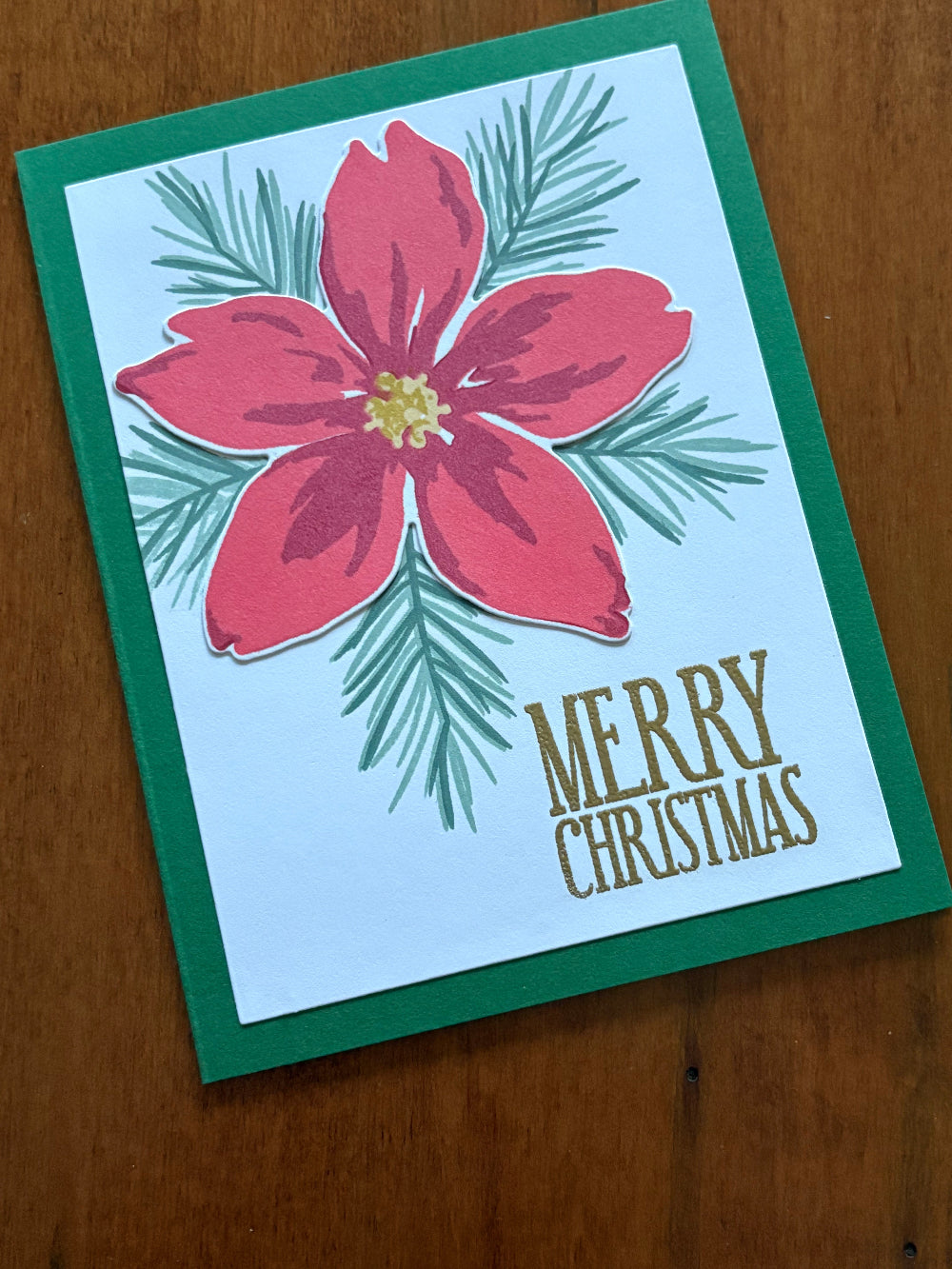 Handmade Christmas card with elegant poinsettia and pine spruce design on white background"