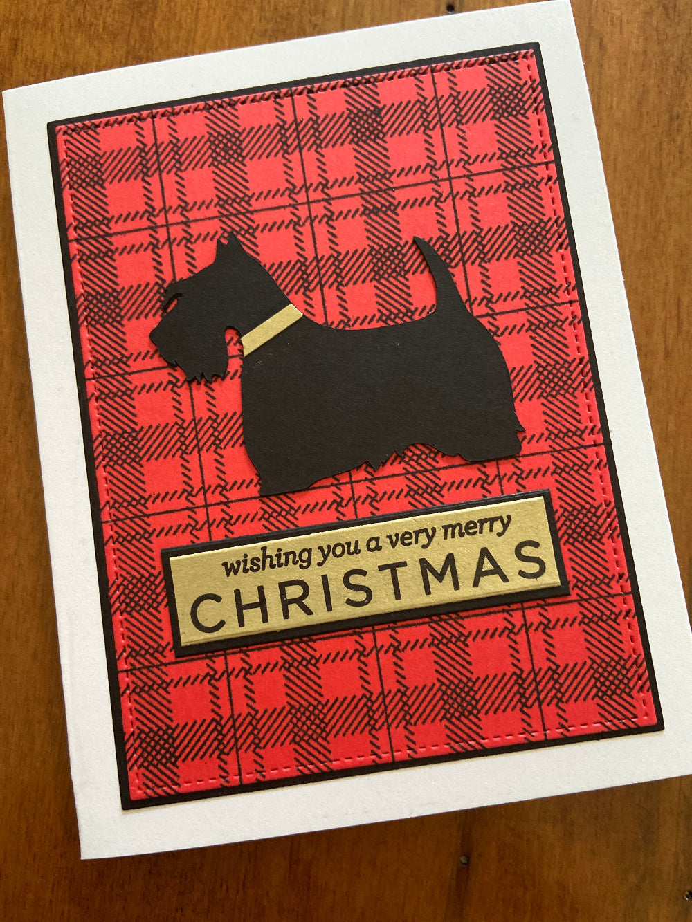 Christmas card with red plaid pattern, black silhouette of Scottish Terrier, and 'Wishing you a very merry Christmas' text.