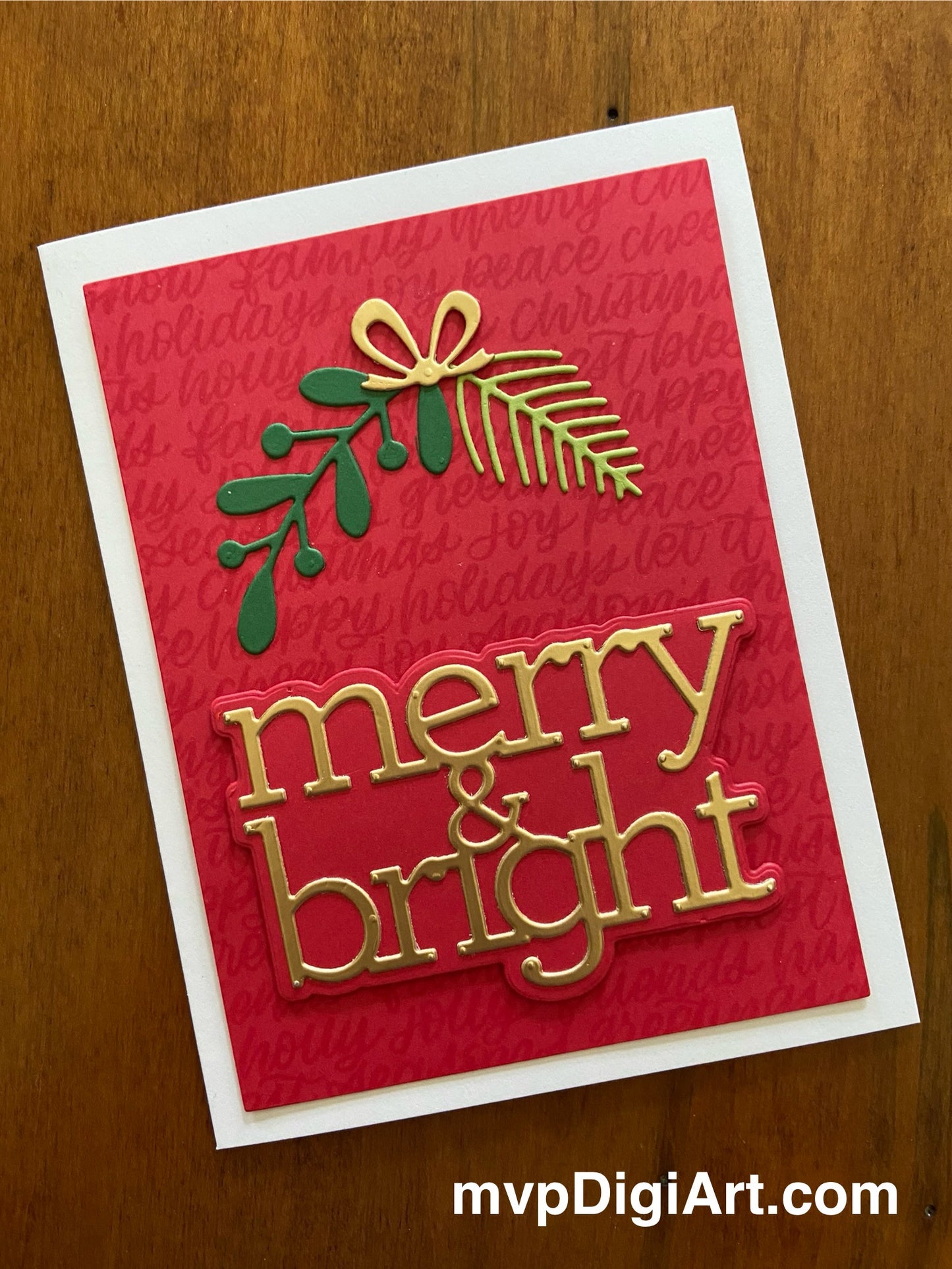 A handmade Christmas card with a red background featuring a die-cut sprig of spruce and a branch of leaves tied together with a lustrous gold bow, and the text 'merry & bright' in golden letters.